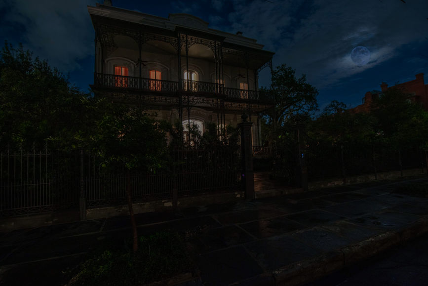 A building with a fence and trees at night.